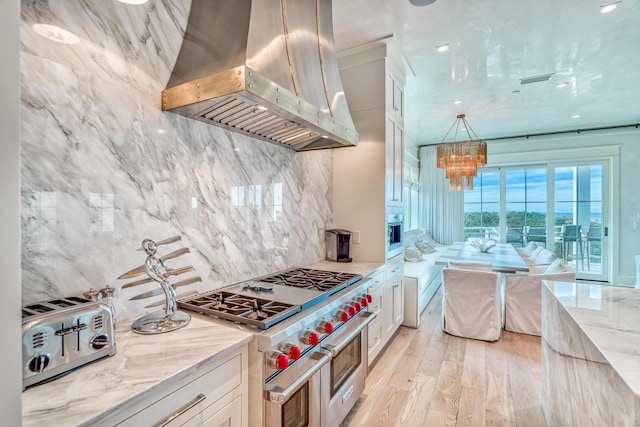 kitchen featuring stainless steel appliances, island exhaust hood, white cabinets, and light stone counters