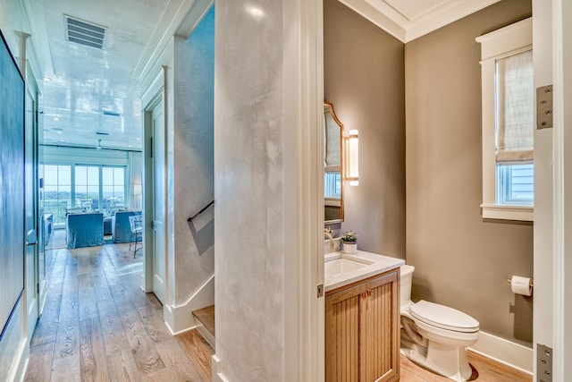 bathroom featuring vanity, crown molding, wood-type flooring, and toilet