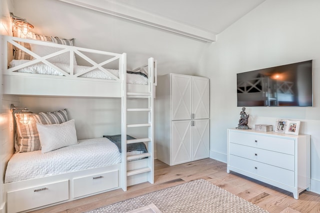 bedroom with light hardwood / wood-style flooring and vaulted ceiling with beams