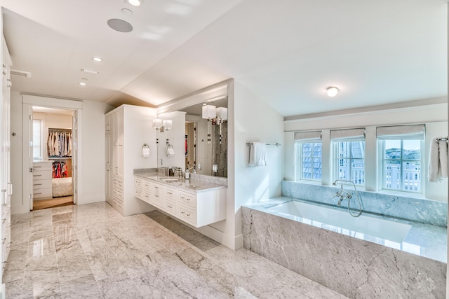 bathroom with tiled tub, vaulted ceiling, and vanity