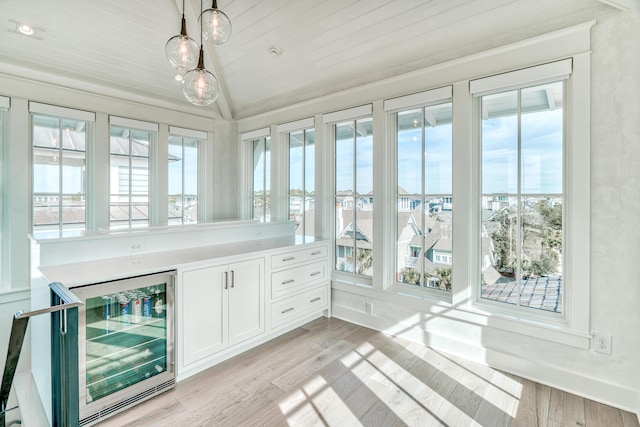 unfurnished sunroom with wine cooler, wood ceiling, a healthy amount of sunlight, and vaulted ceiling