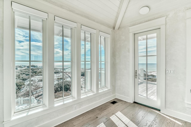 entryway featuring a water view, lofted ceiling with beams, and light wood-type flooring