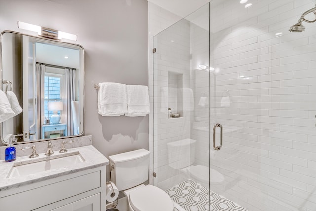 bathroom featuring vanity, a shower with door, and toilet