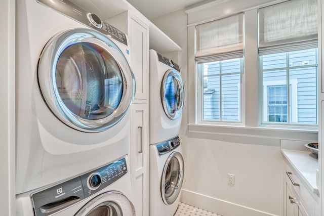 clothes washing area with cabinets and stacked washer and clothes dryer