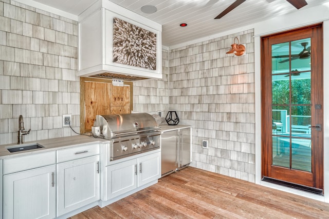 kitchen featuring sink, ceiling fan, white cabinetry, built in fridge, and light wood-type flooring