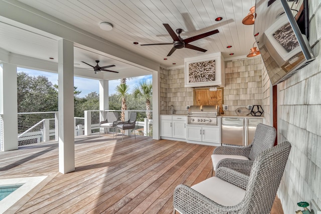 deck with ceiling fan, area for grilling, and exterior kitchen