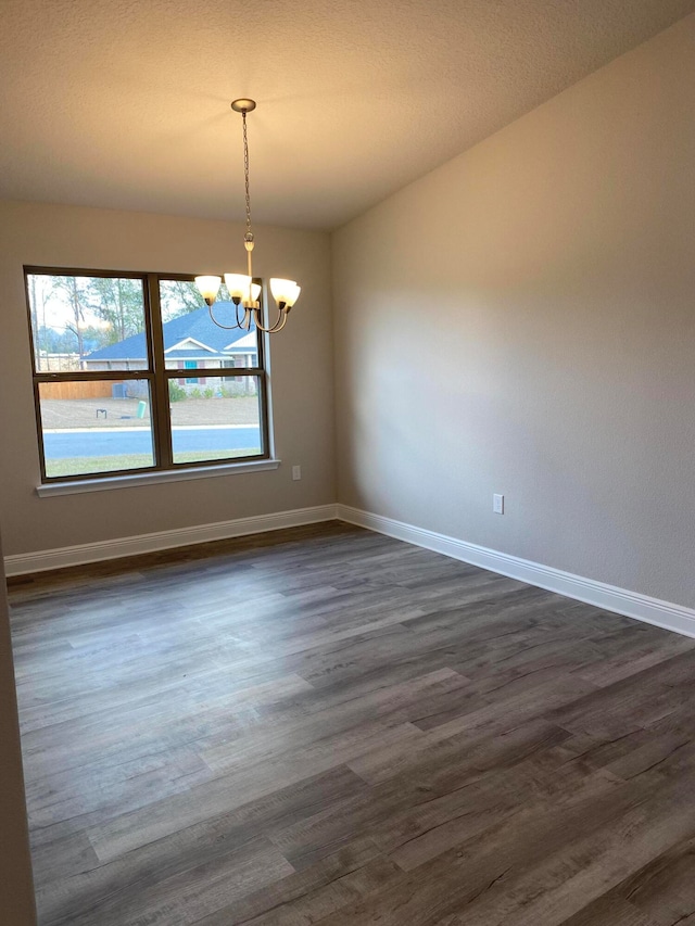 empty room with a chandelier and dark hardwood / wood-style floors