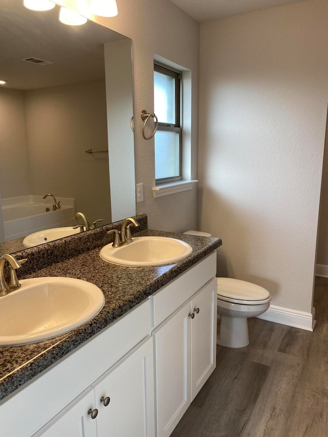 bathroom with vanity, toilet, a tub, and hardwood / wood-style floors