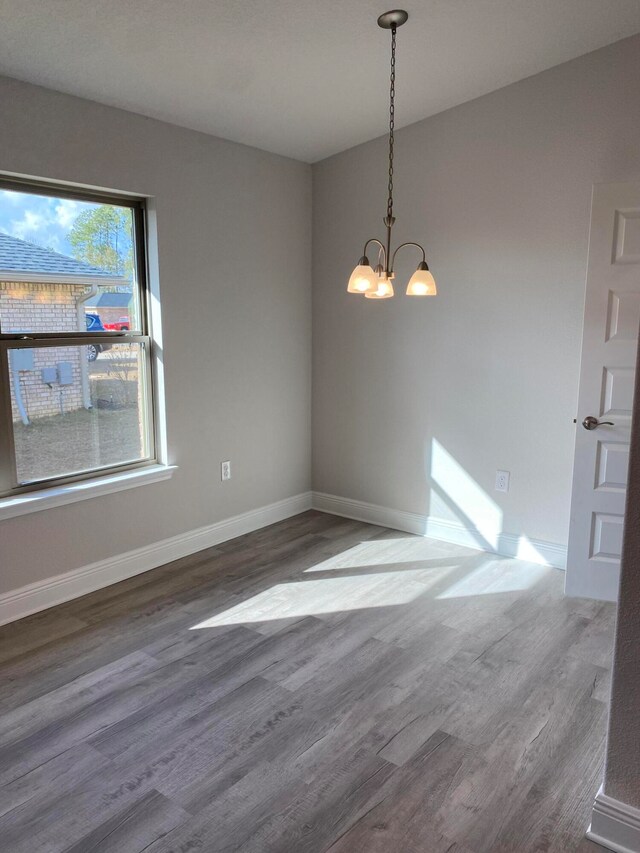 unfurnished dining area with a notable chandelier and hardwood / wood-style flooring