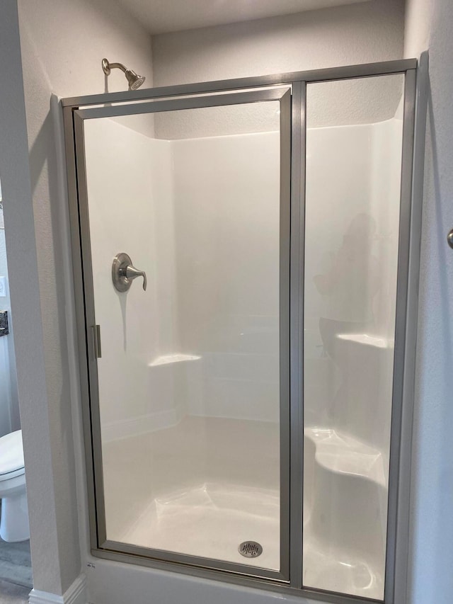 bathroom with wood-type flooring, toilet, and an enclosed shower