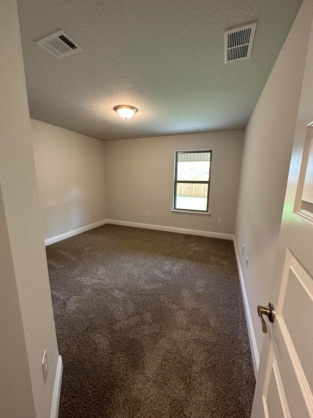 unfurnished room featuring dark carpet and a textured ceiling