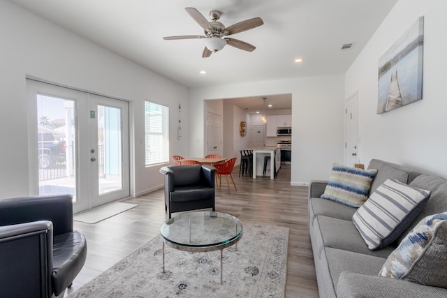 living room featuring french doors, light wood-type flooring, and ceiling fan