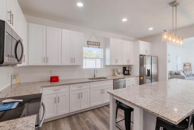 kitchen featuring white cabinets, a kitchen bar, light hardwood / wood-style flooring, sink, and stainless steel appliances