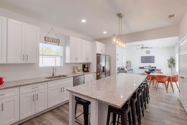 kitchen with stainless steel appliances, a breakfast bar area, light wood-type flooring, and white cabinets