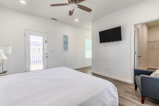 bedroom with a spacious closet, a closet, multiple windows, and hardwood / wood-style floors