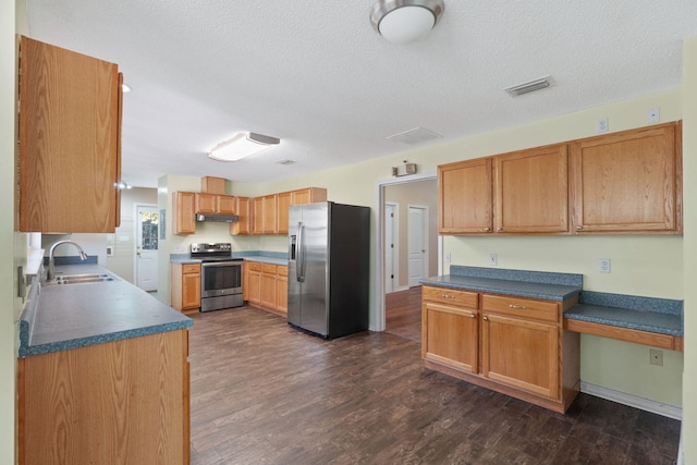 kitchen with dark wood-type flooring, stainless steel appliances, sink, and a textured ceiling