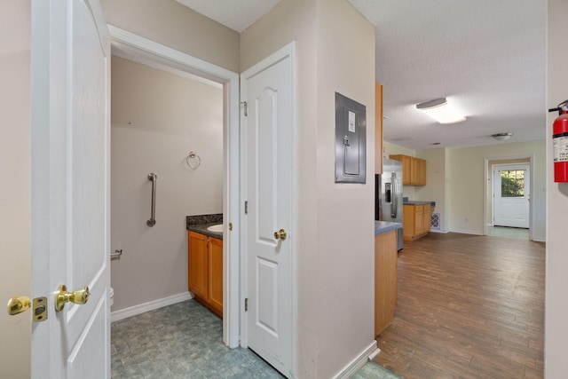 hallway with dark wood-type flooring, a textured ceiling, and electric panel