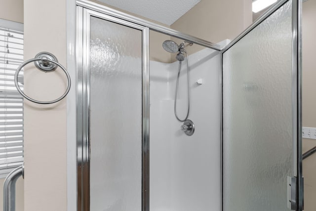 bathroom featuring a shower with door and a textured ceiling