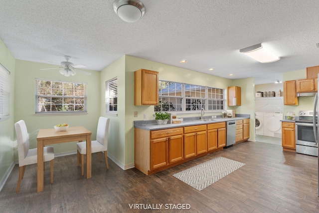 kitchen featuring sink, dark wood-type flooring, washing machine and clothes dryer, and stainless steel appliances