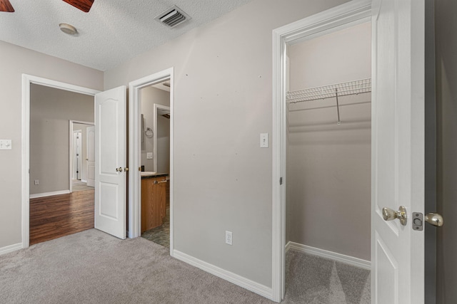 unfurnished bedroom with a closet, ceiling fan, light carpet, and a textured ceiling