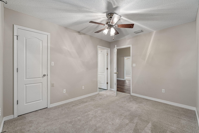 unfurnished bedroom with light carpet, a textured ceiling, and ceiling fan