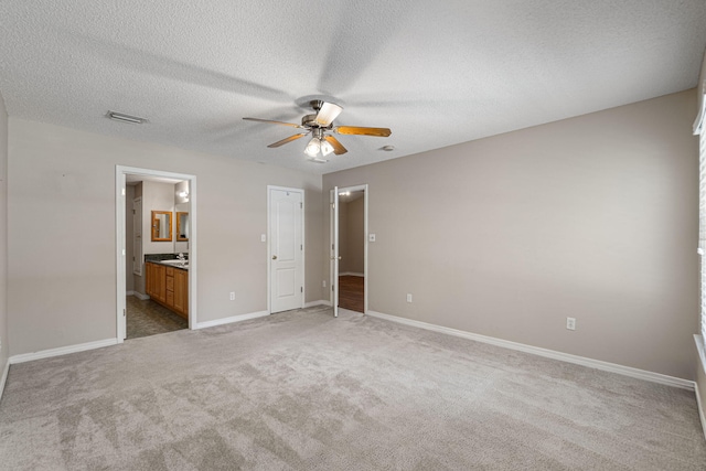 unfurnished bedroom featuring connected bathroom, sink, carpet flooring, a textured ceiling, and ceiling fan