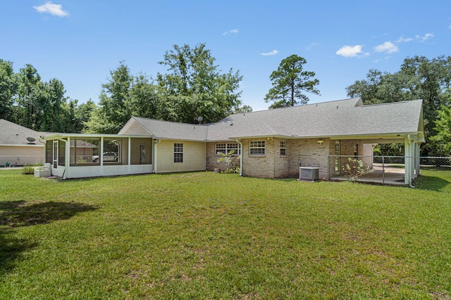 back of property featuring a sunroom, central AC, and a lawn