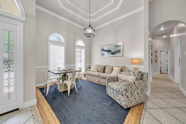 living room featuring a towering ceiling, light tile patterned floors, ornamental molding, and a wealth of natural light