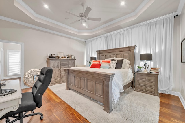 bedroom with crown molding, a tray ceiling, light wood-type flooring, and ceiling fan