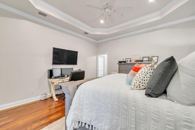 bedroom featuring crown molding, hardwood / wood-style flooring, a tray ceiling, and ceiling fan