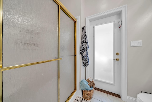 bathroom featuring toilet, an enclosed shower, and tile patterned flooring