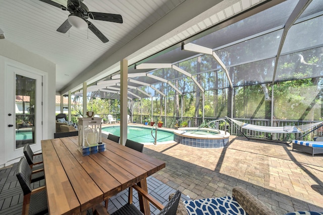 view of patio / terrace featuring ceiling fan, glass enclosure, and a swimming pool with hot tub