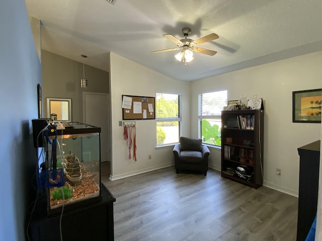 sitting room with ceiling fan, lofted ceiling, wood-type flooring, and a textured ceiling