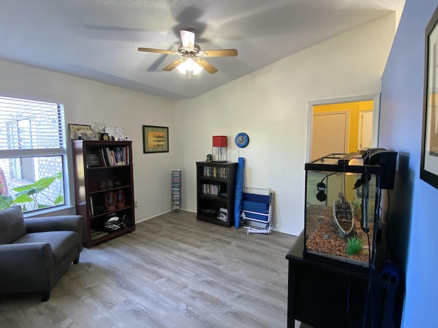 living area featuring hardwood / wood-style flooring, ceiling fan, and a textured ceiling