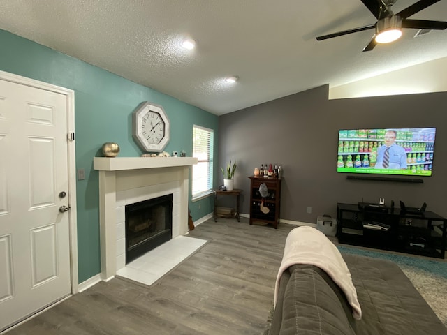 living room with lofted ceiling, hardwood / wood-style floors, a textured ceiling, and ceiling fan