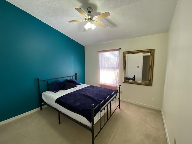 bedroom featuring ceiling fan, light carpet, and a textured ceiling