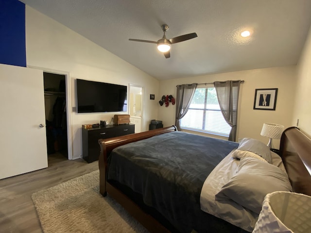 bedroom featuring lofted ceiling, ceiling fan, wood-type flooring, a textured ceiling, and a closet