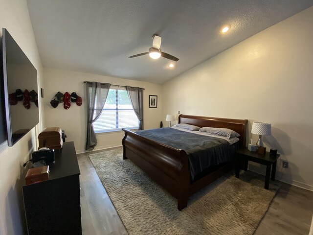 bedroom featuring lofted ceiling, a textured ceiling, wood-type flooring, and ceiling fan