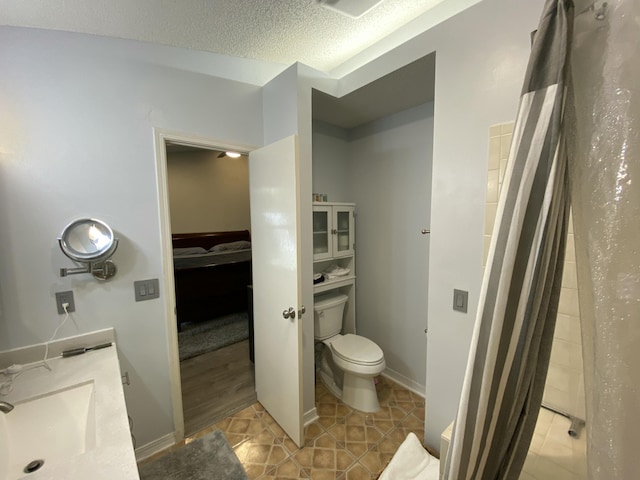 bathroom featuring tile patterned flooring, vanity, a textured ceiling, toilet, and walk in shower