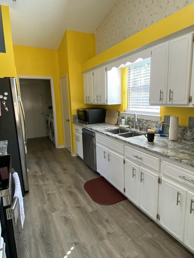 kitchen with sink, washer and clothes dryer, stainless steel appliances, and white cabinets