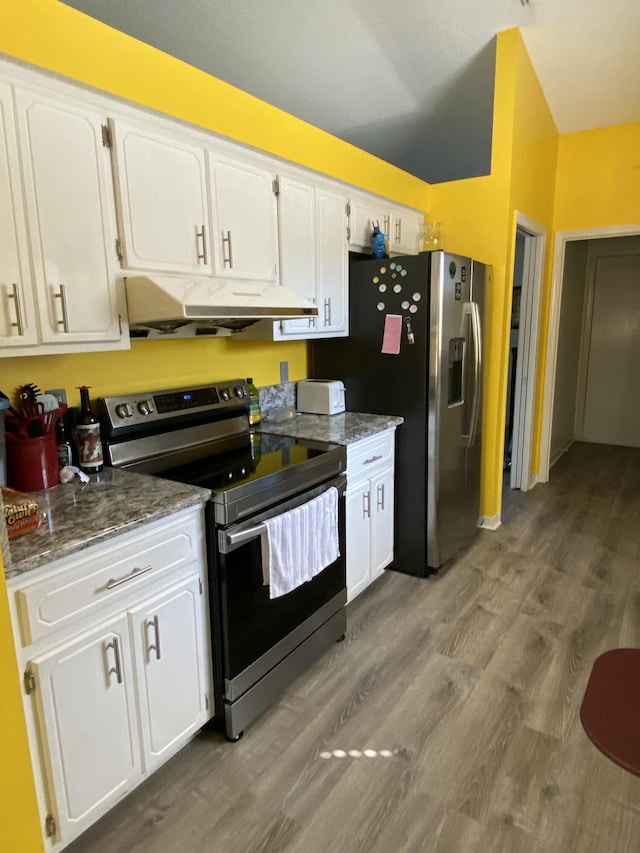 kitchen featuring stainless steel appliances, white cabinetry, hardwood / wood-style floors, and dark stone counters