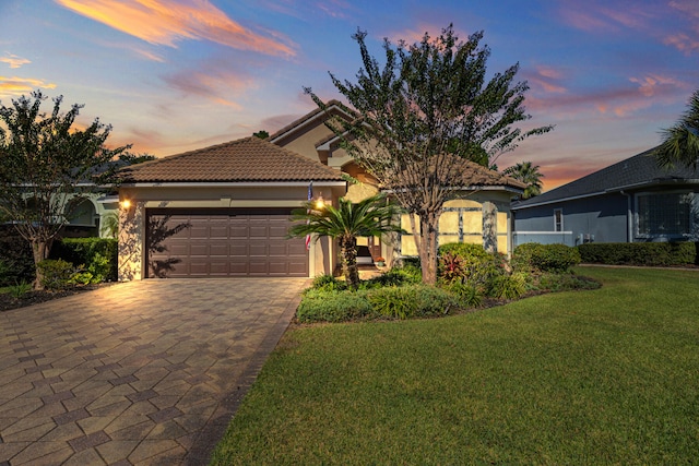 mediterranean / spanish-style house featuring a garage and a yard