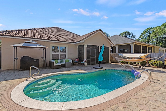 view of swimming pool with an outdoor hangout area, pool water feature, a sunroom, and a patio area