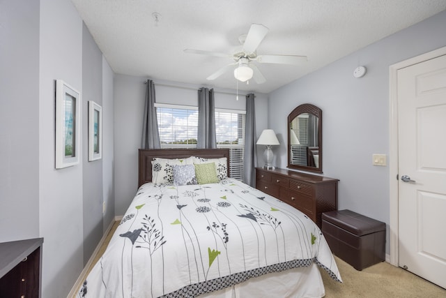 bedroom featuring light carpet, a textured ceiling, and ceiling fan