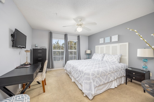 carpeted bedroom featuring ceiling fan and a textured ceiling