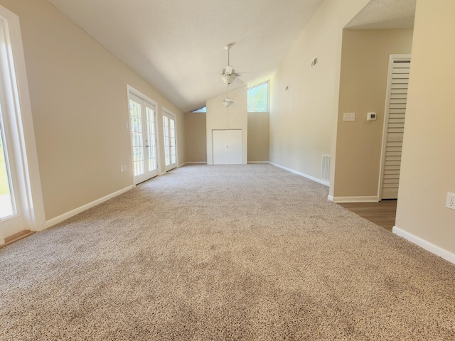 unfurnished living room with dark colored carpet, lofted ceiling, plenty of natural light, and ceiling fan