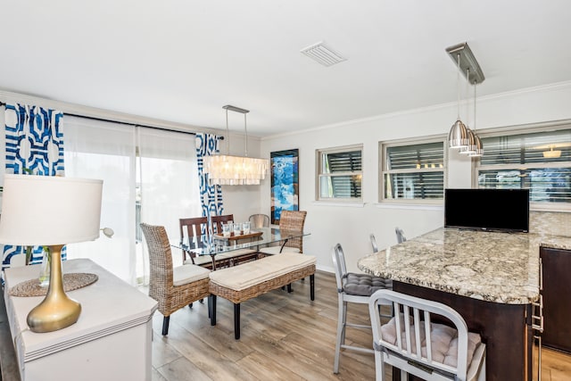 dining space with an inviting chandelier, crown molding, and light hardwood / wood-style floors