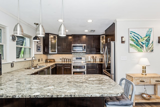 kitchen with dark brown cabinets, ornamental molding, hardwood / wood-style floors, sink, and appliances with stainless steel finishes