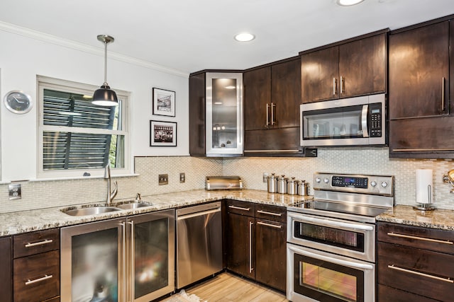 kitchen featuring light stone counters, stainless steel appliances, dark brown cabinetry, and sink