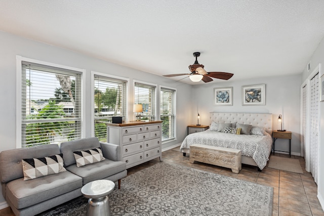 bedroom featuring a textured ceiling, tile patterned floors, and ceiling fan